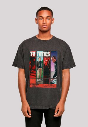 Man wearing black faded T-shirt with retro TV Times magazine cover featuring four men in different poses and colors.