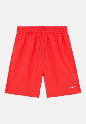 Pantaloni scurți atletici roșii cu talie elastică și un mic logo Nike alb în formă de swoosh pe partea dreaptă jos a piciorului, așezați pe o suprafață albă.