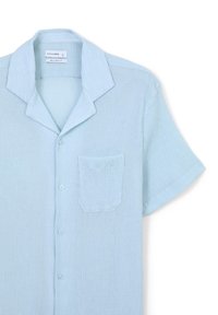 Camicia a maniche corte blu chiaro con vestibilità ampia, tessuto testurizzato, colletto piatto, chiusura con bottoni e taschino singolo sul petto.