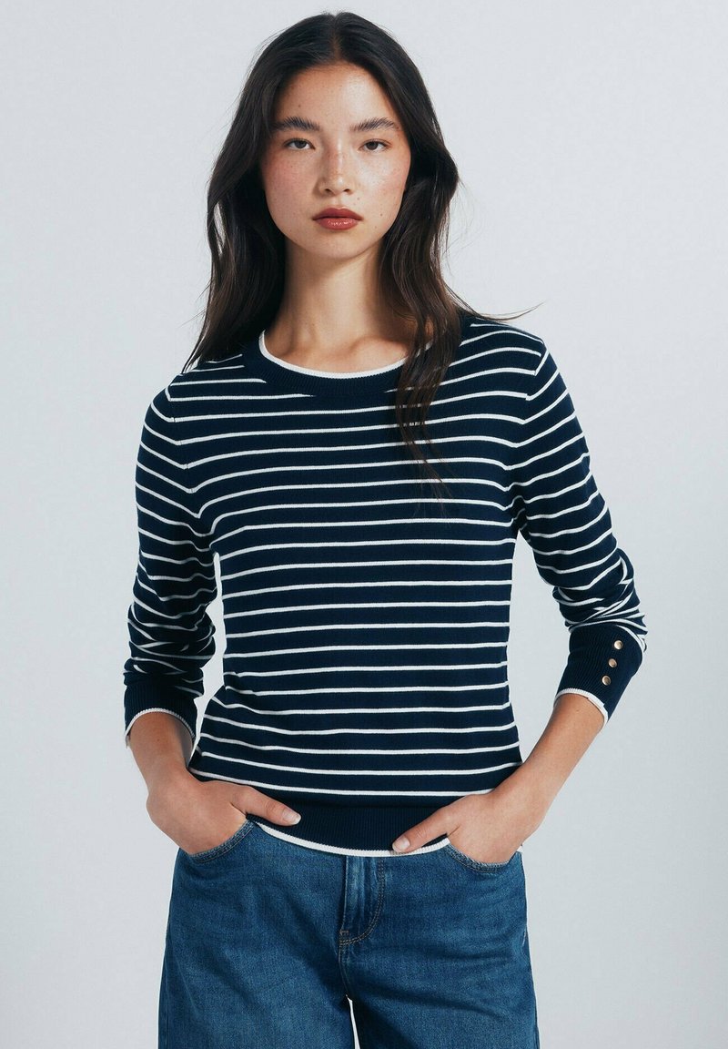 Marinblå och vit randig tröja med rund halsringning, långa ärmar och guldkallbackar vid ärmsluten. Bomullsblandat tyg, ribbad nederkant.