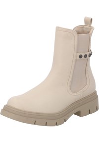 Botín beige hasta el tobillo con un upper sintético suave, paneles laterales elásticos, botones decorativos y una suela de goma gruesa con profundas huellas.