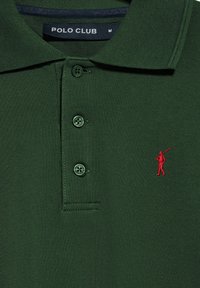 Donkergroene polo shirt van gestructureerde stof, met drie groene knopen en een rood geborduurd golflogo. Het label zegt "POLO CLUB."