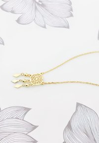 Guldkedja med en cirkulär medaljong med blommiga utskärningsmönster, accentuerad av runda och diamantformade pärlor längs kedjan.