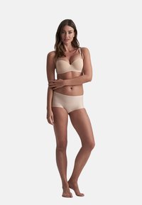 Beige lingerie set met een gladde, gevoerde beha met verstelbare straps en naadloze, low-rise slipjes. Zachte stof met een minimalistisch ontwerp.