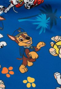 Tessuto blu con personaggi di cani dei cartoni animati caratteristici, inclusi un cane marrone vestito di blu e impronte di zampe in arancione e giallo.