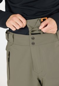 Olivgrüne Skihose mit einer Reißverschlusstasche, Druckknöpfen, verstellbarem Bund und einer glatten, wasserabweisenden Stoffstruktur.