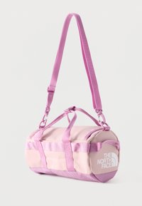 Roza valjasta torba s prilagodljivim naramnim trakom in dvojnimi ročaji, z belim logotipom The North Face na strani.
