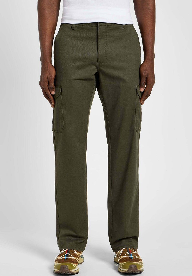 Pantaloni cargo olive con vestibilità dritta, dotati di tasche laterali e un tessuto robusto. Abbinati a sneakers marroni per un contrasto.