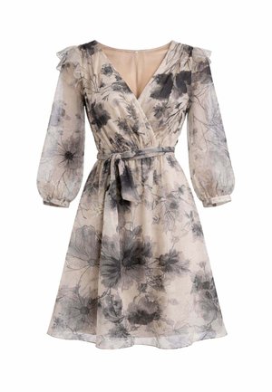 Vestito beige fino al ginocchio con stampa floreale nera, scollo a V, maniche lunghe trasparenti a sbuffo, dettagli con volant sulle spalle e cintura annodata in vita.