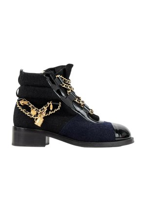 Bottine noire et bleu foncé à talon bas, bout brillant, lacets en cuir verni et chaîne décorative dorée avec breloques entourant la chaussure.