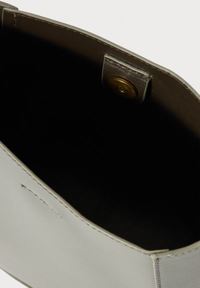 Borsa a mano in pelle grigia chiara con una texture liscia, caratterizzata da un design semplice, un interno scuro e una chiusura a clip in ottone.