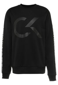 Sweat-shirt en coton noir avec un grand logo "CK" noir sur le devant et du texte blanc le long des manches. Poignets et ourlet côtelés.