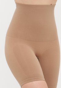Shorts modellanti a vita alta in un tessuto liscio color beige. Presentano un design senza cuciture e una texture leggera e elastica per il massimo comfort.