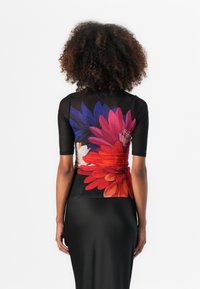 Bloemmotief top met korte mouwen, met levendige rode, roze en paarse bloemen op een zwarte achtergrond, gecombineerd met een strakke zwarte rok.