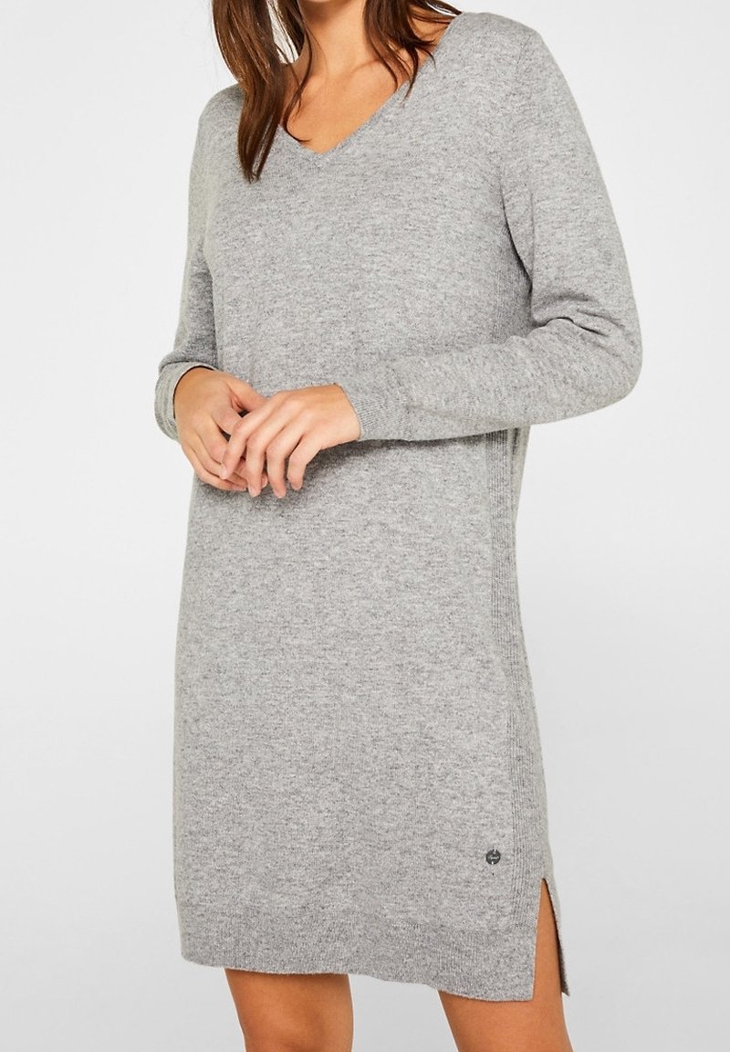 Vestito grigio di maglia con scollo a V, maniche lunghe, spacchi laterali e piccolo dettaglio logo sull'orlo. Tessuto morbido e vestibilità rilassata.