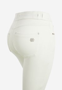 Jeans skinny bianchi realizzati in tessuto elasticizzato, con vita alta, due tasche posteriori e dettagli in metallo argentato. Texture liscia e forma aderente.
