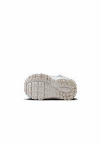 Podeszwa trampka z teksturowanym gumowym spodem o wyraźnych wzorach bieżnika, w większości biała z lekkim szarym akcentem.