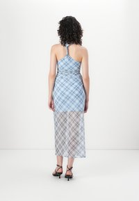 Blauw geruit halterjurk met een aansluitend lijfje en een semi-doorzichtige lange rok. Beschikt over een crisscross achterkant en delicate, dunne schouderbandjes.