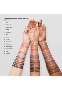 Zwei Arme zeigen Farbmuster von Cream Shadow Sticks vor einem grauen Hintergrund. Die Farben reichen von hellen Rosa- bis zu tiefen Brauntönen, nummeriert von 1 bis 19.