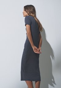 Striped navy dress made of soft fabric, short sleeves, fitted silhouette, mid-length, with a simple design and rounded neckline.