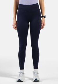 Marineblaue High-Waist-Leggings aus dehnbarem Stoff, mit einer glatten Textur und einem kleinen Logo-Emblem am linken Oberschenkel.