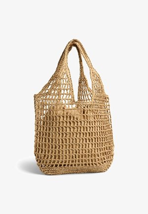 Beige vævet net indkøbsnet med to håndtag, der viser en solid beige pung indeni, mod en hvid baggrund.