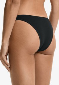 Svart bikiniunderdel i ribbat tyg, med hög skärning och minimal baksida samt släta kanter.