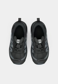 Schwarze Sport Schuhe mit einer strukturierten Oberfläche, ausgestattet mit grauen Akzenten und einem schnellen Schnürsystem. Enthält eine Zuglasche an der Ferse.