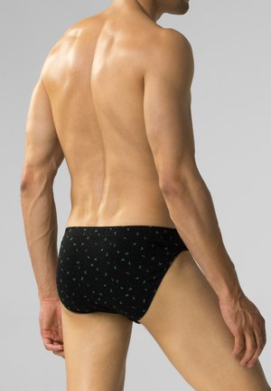 Czarne kąpielówki z małym zielonym wzorem liści, elastycznym paskiem w talii i obcisłym krojem, zaprojektowane z myślą o komforcie i elastyczności.