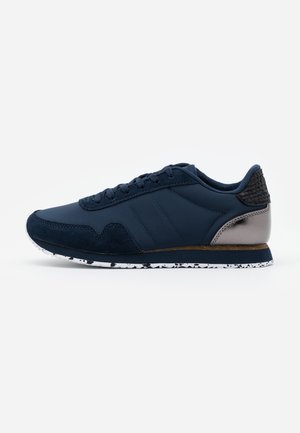 Mørkeblå sneakers med en glatt lær- og semsket overdel, teksturert bakside, hvit flekkete såle og et lagdelt design.