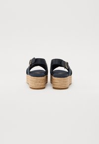 Sandalias azul marino con tiras cruzadas, que cuentan con un tacón de plataforma de yute trenzado, hebilla ajustable y suela texturizada.