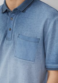 Niebieska koszulka polo o teksturowanym wykończeniu, z trzema guzikami, kieszenią na piersi oraz kontrastowymi czarnymi detalami na kołnierzyku i mankietach.