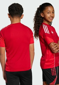 Rode sportieve jersey met korte mouwen, voorzien van witte accentstrepen op de schouders en zijkanten. Gladde textuur, ontspannen pasvorm, ontworpen voor sportactiviteiten.