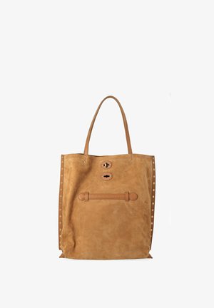 Bolso tote de ante color marrón claro con doble asa para el hombro, tachuelas laterales y dos cierres delanteros de tiras de cuero sobre fondo blanco.