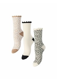 Trois paires de chaussettes avec des designs différents : une avec un imprimé léopard beige, une blanche côtelée avec des accents noirs, et une avec un imprimé léopard noir.