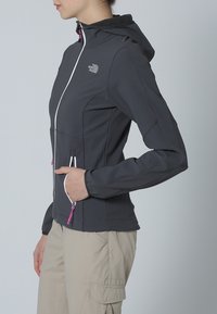Graue Softshell-Jacke mit einem Reißverschluss vorne, weißen Akzenten und einer Kapuze. Verfügt über zwei Reißverschlusstaschen und elastische Bündchen.