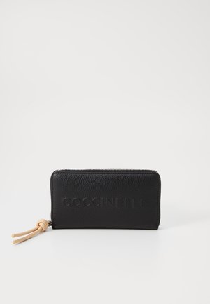 Portafoglio in pelle nera con superficie texturizzata, dotato di chiusura con zip e linguetta in pelle, impressa con "COCCINELLE" sulla parte anteriore.
