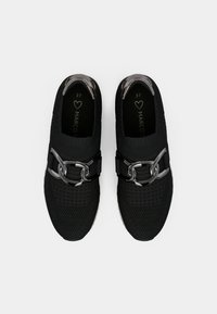 Μαύρα αθλητικά παπούτσια με υφασμάτινο επάνω μέρος με υφή, διαθέτοντας μια στιλάτη μεταλλική ζώνη με κυκλική προσθήκη και λευκή σόλα. Μέγεθος 37.