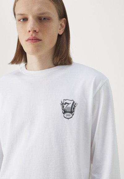 White long-sleeve t-shirt made of cotton featuring a printed logo with the number "7" and "7 DAY ACTIVE" on the left chest area.