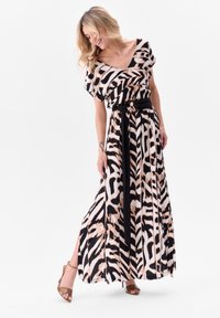 Robe maxi en tissu à motifs, avec un col en v, des manches courtes, une ceinture noire, et un mélange de rayures zébrées beiges et noires.