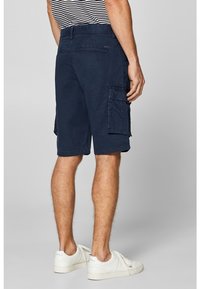 Shorts cargo bleu marine en mélange de coton avec poches latérales et coupe décontractée, associés à des baskets blanches et un haut rayé.