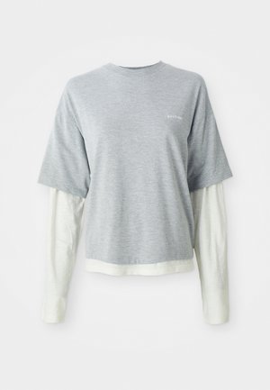 Gray short-sleeve t-shirt layered over a white long-sleeve shirt, both in soft cotton fabric. Features a small logo on the chest.