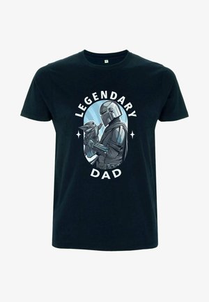 Černé tričko s grafikou postavy, která drží menší figurku; text zní "LEGENDÁRNÍ TÁTA" bílým písmem v kruhovém designu.