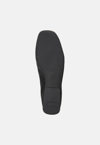 Suola di scarpa nera con una superficie liscia, caratterizzata da un motivo di presa texture e un piccolo tacco quadrato. Design piatto senza branding visibile.