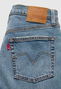 Μπλε τζιν παντελόνια από denim με δερμάτινη ετικέτα που αναγράφει "Levi Strauss & Co." στο πίσω μέρος, με χαρακτηριστικό σχέδιο ραφής arcuate στις τσέπες.