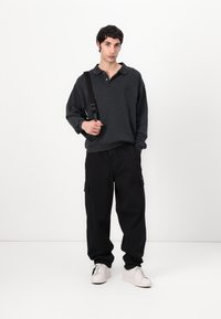 Dark gray sweatshirt with a collared neck, paired with black cargo pants featuring side pockets and white sneakers. Simple, casual design.