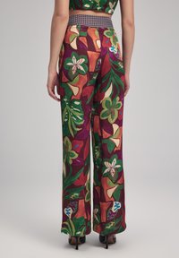 Wijdbenige broek in een levendige bloemenprint, met groen, paars en rood; soepel materiaal met een textuurband.