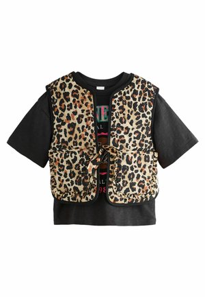Gilet à imprimé léopard avec deux poches avant, porté par-dessus un t-shirt graphique noir. Le gilet présente un col rond et une fermeture à nouer.