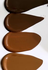 Fire svamper i ulike nyanser av brunt, med glatte, blanke teksturer på en hvit bakgrunn. Hver svamp har en dråpeform.