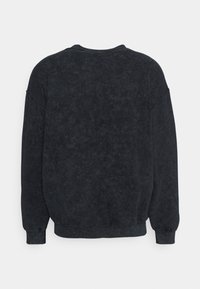 Tmavě šedá, oversize mikina s měkkou, texturovanou látkou; má kulatý výstřih a dlouhé rukávy s žebrovanými manžetami.